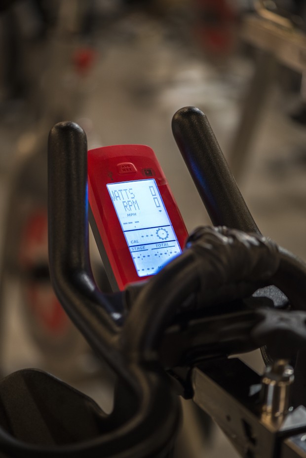 The Schwinn bike monitor indicates the rider's RPM, gear level, and wattage.